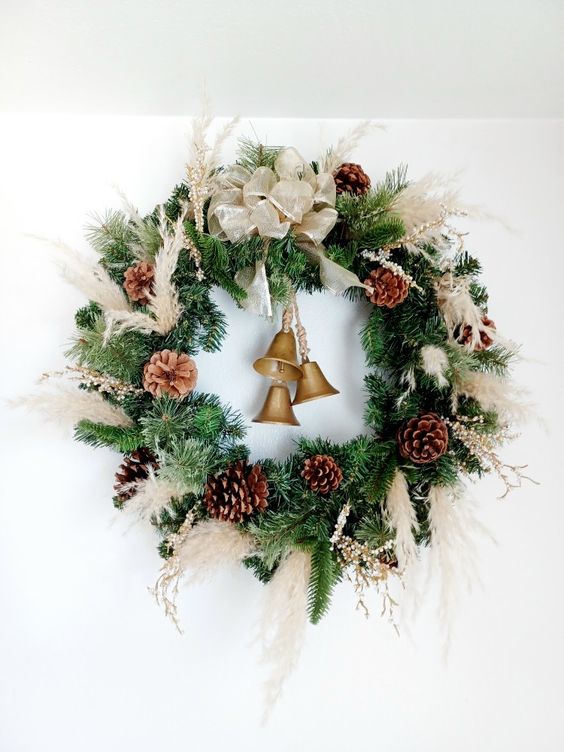a Christmas wreath of evergreens, pampas grass, pinecones, bells and a large neutral bow is a chic idea