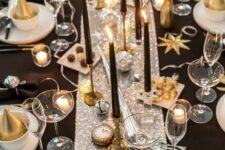 24 a shiny glam NYE tablescape with a silver sequin runner, white porcelain, black candles, gold cutlery and clocks and disco balls