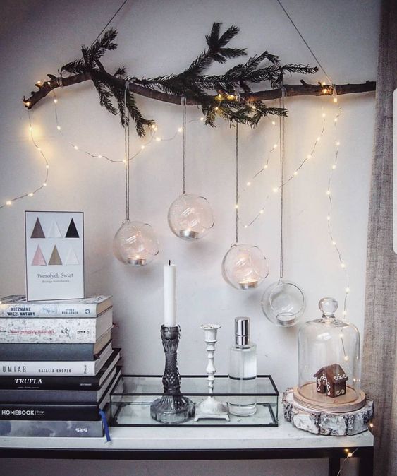 a Christmas wall hanging with lights, an evergreen branch and some baubles wih tealights is a great solution