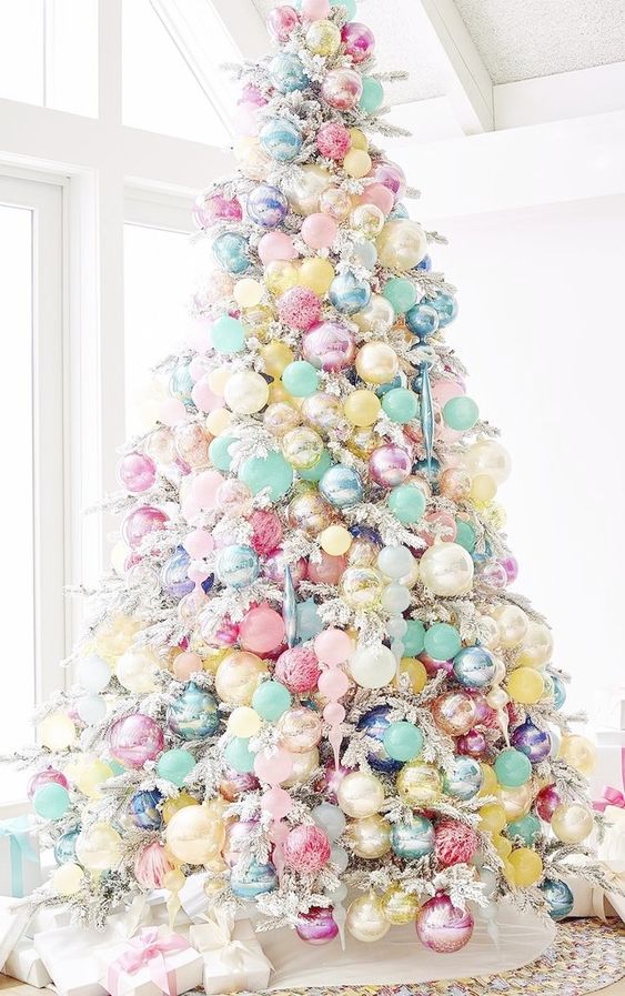 a flocked Christmas tree decorated with candy-colored ornaments that cover the whole tree