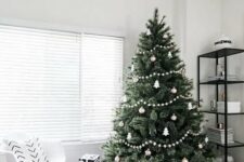 25 a minimalist Scandi Christmas tree decorated with white and silver ornaments, white pompom garlands and a basket plus black and white gift boxes