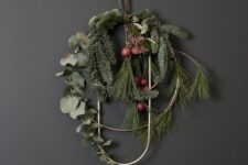 26 a modern Christmas wreath of a gold circle and curve, with evergreens, greenery and berries is a lovely idea