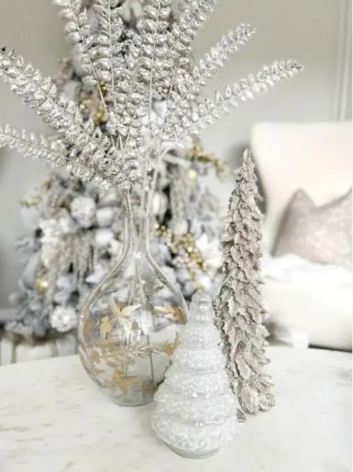 a silver Christmas arrangement with silver foliage, a snowy Christmas tree and a glass one is beautiful