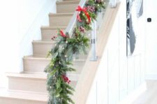 26 an evergreen Christmas garland with lights, berries and red bows plus pinecones looks very festive and super natural
