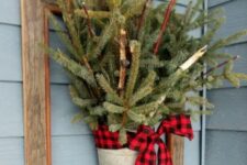 27 a frame with a bucket with fir branches and a red plaid bow is an easy DIY decoration for your front door or wall