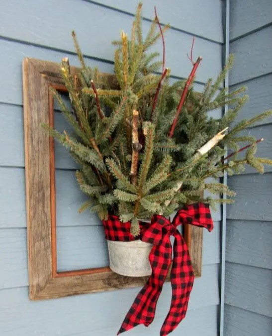 a frame with a bucket with fir branches and a red plaid bow is an easy DIY decoration for your front door or wall