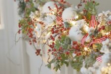 27 an evergreen Christmas garland with snow, red berries, striped ribbons and lights is a cool idea for winter