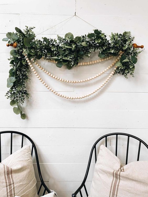 a lovely Christmas wall decoration of greenery, wooden bead garlands is a cool solution for any space of your home