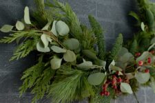 28 a modern Christmas wreath with evergreens and foliage plus berries is a stylish idea for a modern holiday space