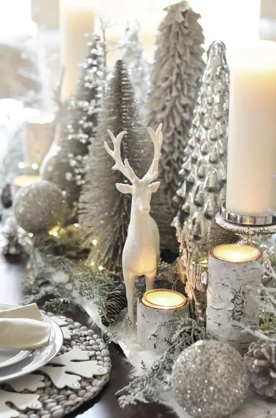 a silver Christmas centerpiece of silver glitter ornaments, silver evergreens, candleholders, silver Christmas trees