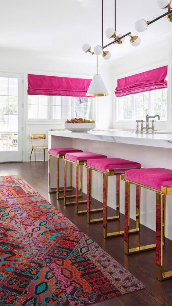 a refined modern all-white kitchen with magenta stools and curtains that bring color and interest to the clean and neutral space
