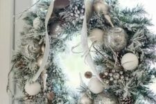 29 a silver Christmas wreath with snowy pinecones and a bow on top is a chic idea for Christmas decor