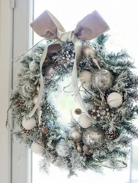 a silver Christmas wreath with snowy pinecones and a bow on top is a chic idea for Christmas decor