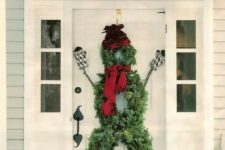 29 a snowman front door decoration of evergreen wreaths, a red scarf and beanie, sticks and mittens is a fun idea