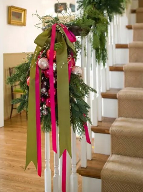 an evergreen garland paired with green and hot pink ribbons and pastel ornaments for lovely Christmas railing decor