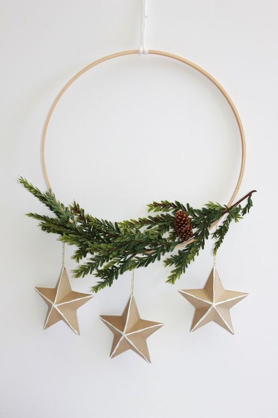 a modern Christmas wreath with evergreens, a pinecone and a trio of cardboard stars is a catchy and lovely idea
