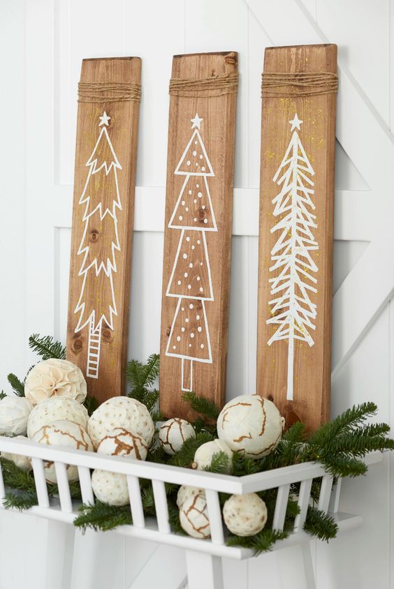 a pretty Christmas wall decoration of three wooden panels as signs, a basket with decorated ornaments and evergreens is a cool idea