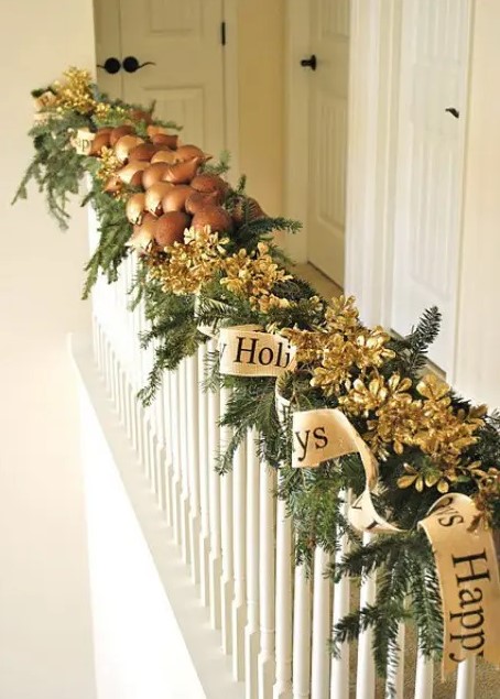 an evergreen garland with gilded pinecones, mushrooms and a gold ribbon are amazing decor for Christmas banisters