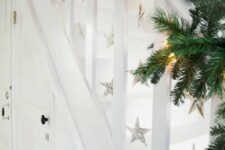 31 an evergreen garland with lights and music sheet stars hanging down are a beautiful solution for a Christmas space