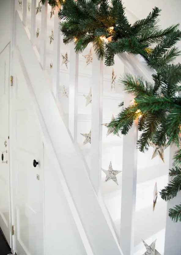 an evergreen garland with lights and music sheet stars hanging down are a beautiful solution for a Christmas space