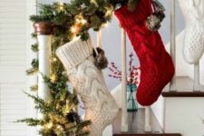 32 an evergreen garland with lights and pinecones plus red and white stockings hanging down are a great Christmas decoration for a banister