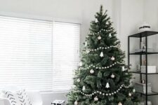 33 a minimalist Scandi Christmas tree decorated with white and silver ornaments, white pompom garlands and a basket plus black and white gift boxes