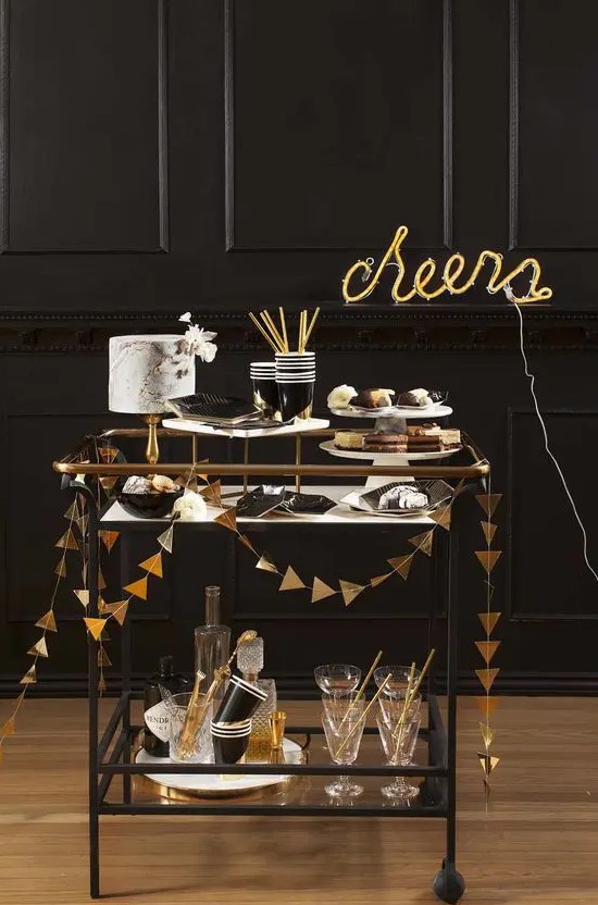 a simple black bar cart decorated with a gold foil triangle garland and a neon sign is a great idea for a NYE party
