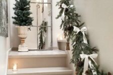 33 an evergreen garland with pinecones, tassels, white bows and candle lanterns right on the steps are amazing for the holidays