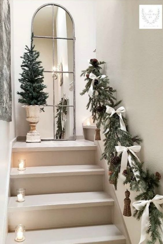 an evergreen garland with pinecones, tassels, white bows and candle lanterns right on the steps are amazing for the holidays