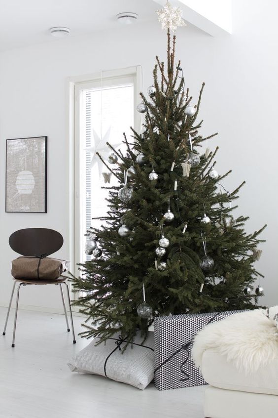 a minimalist Christmas tree with silver and clear smoked glass ornaments plus a star topper is a stylish idea