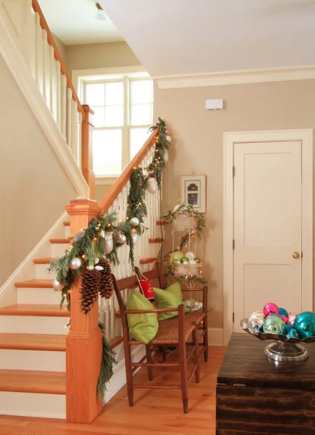 an evergreen garland with silver ornaments, lights and pinecones is a lovely decoration for railings at Christmas