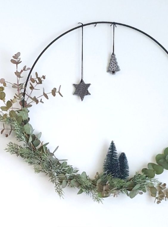 a modern meets Scandi Christmas wreath with greenery, leaves, bottle brush trees and some plywood ornaments hanging