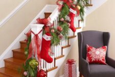 35 bold Christmas railing decor with red, white and grene ornaments, evergreens, pinecones, stockings and large red bows