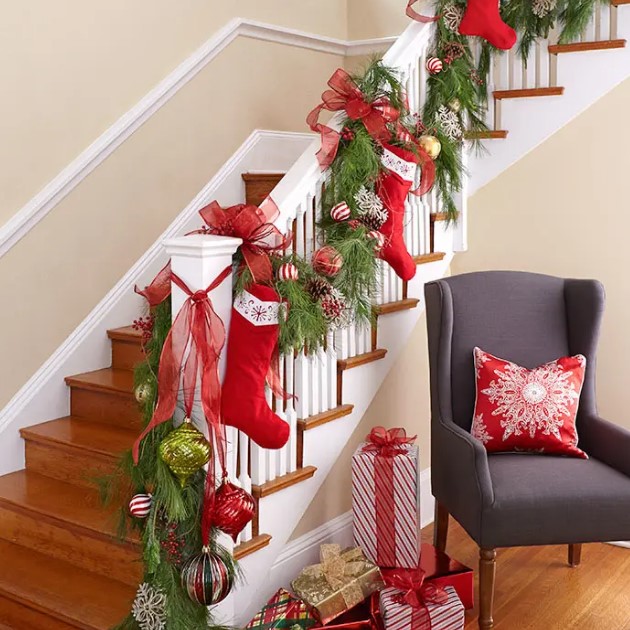 bold Christmas railing decor with red, white and grene ornaments, evergreens, pinecones, stockings and large red bows