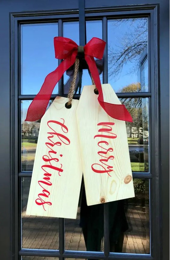 giant tags of wooden boards and a red bow on top is a lovely idea for styling your front door at Christmas