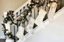 37 Christmas railing decor with white embellished stockings, an evergreen garland with lights and white and silver ornaments