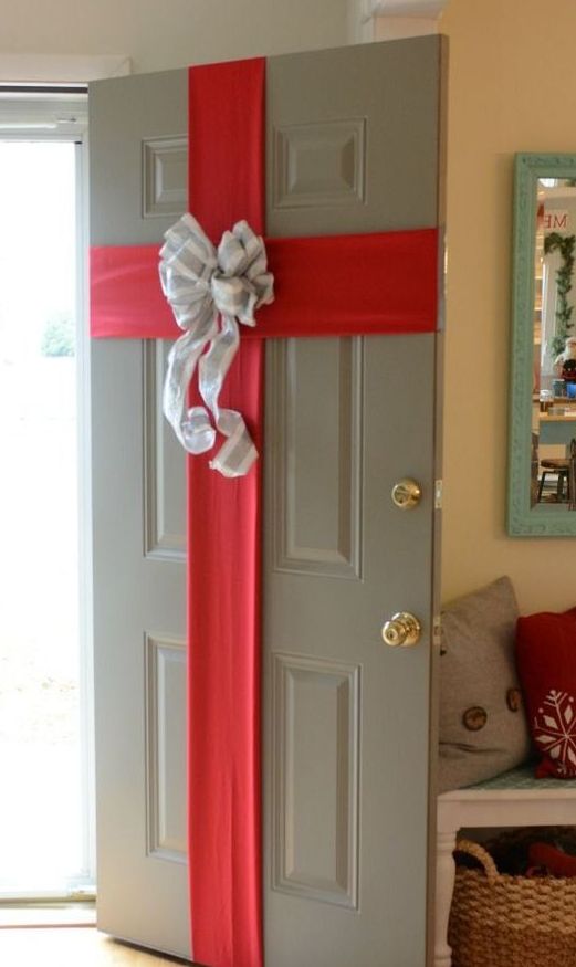 a front door styled as a Christmas gift box, with red ribbon and a large bow, looks cute