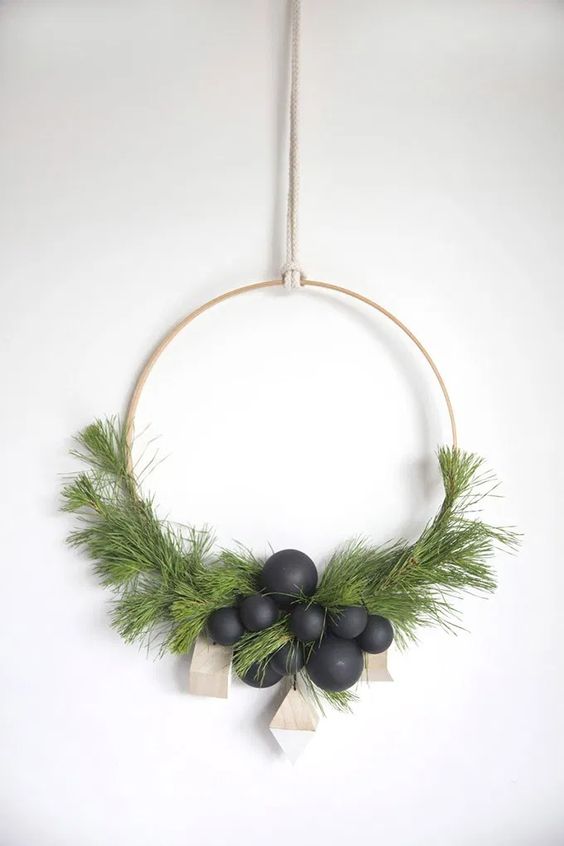 a modern Scandinavian Christmas wreath with evergreens, matte black ornaments and wooden geometric ornaments is wow