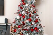 37 a stylish flocked Christmas tree decorated with silver, white and red ornaments, berry branches and letters