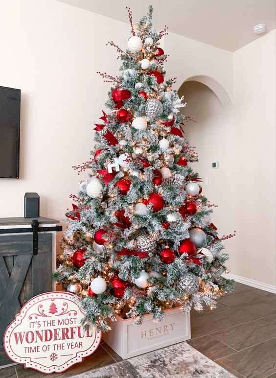 a stylish flocked Christmas tree decorated with silver, white and red ornaments, berry branches and letters