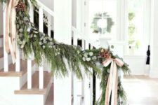 38 Christmas railing decorated with an evergreen, eucalyptus, pinecone and ribbon bow garland looks very festive and cool