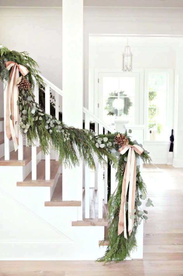 Christmas railing decorated with an evergreen, eucalyptus, pinecone and ribbon bow garland looks very festive and cool