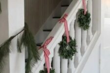 39 cool eucalyptus wreaths with red striped ribbon and an evergreen garland are a nice combo for Christmas staircase decor