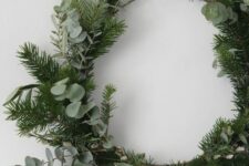 41 a simple and lovely Christmas wreath covered with evergreens and eucalyptus is a beautiful winter decor idea that will be actual after Christmas, too