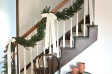 41 elegant farmhouse Christmas railing decorated with an evergreen garland with large neutral bows is a stylish idea