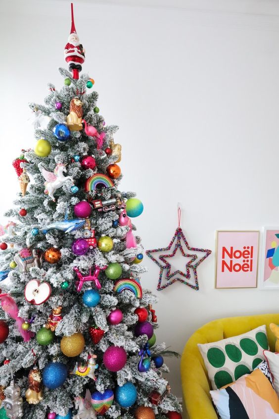 a flocked Christmas tree decorated in all the colors of the rainbow, with bold ornaments, rainbows, apples and a unicorn