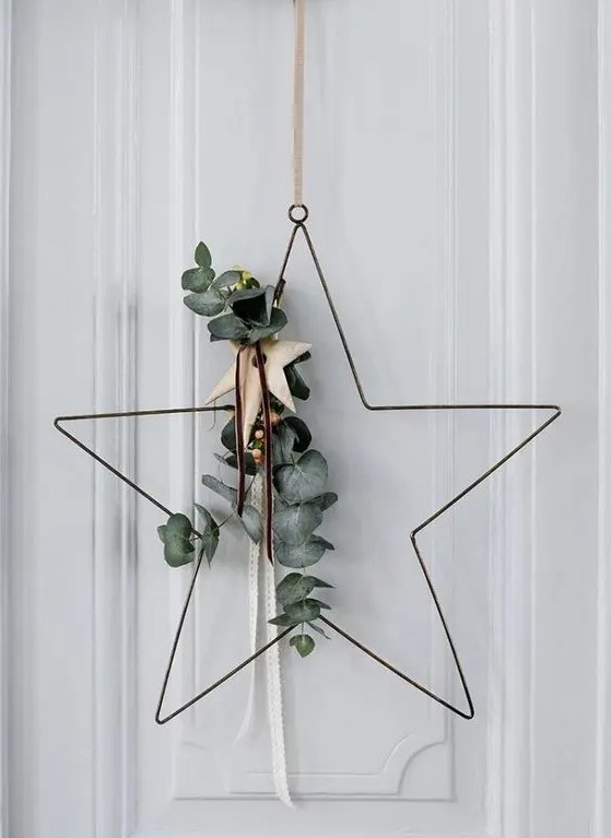 a star-shaped Christmas wreath with eucalyptus, with wooden stars is a cool and contemporary idea for door decor