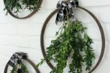 49 an arrangement of embroidery hoops, with greenery and buffalo check bows on top is a great idea for a modern Christmas space