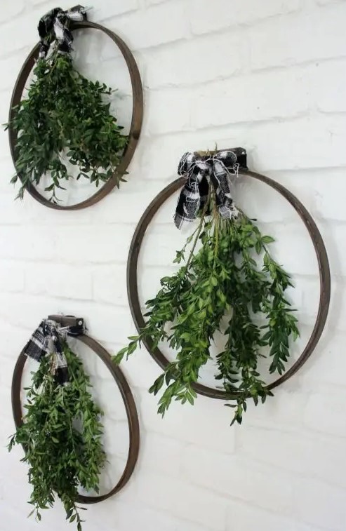 an arrangement of embroidery hoops, with greenery and buffalo check bows on top is a great idea for a modern Christmas space