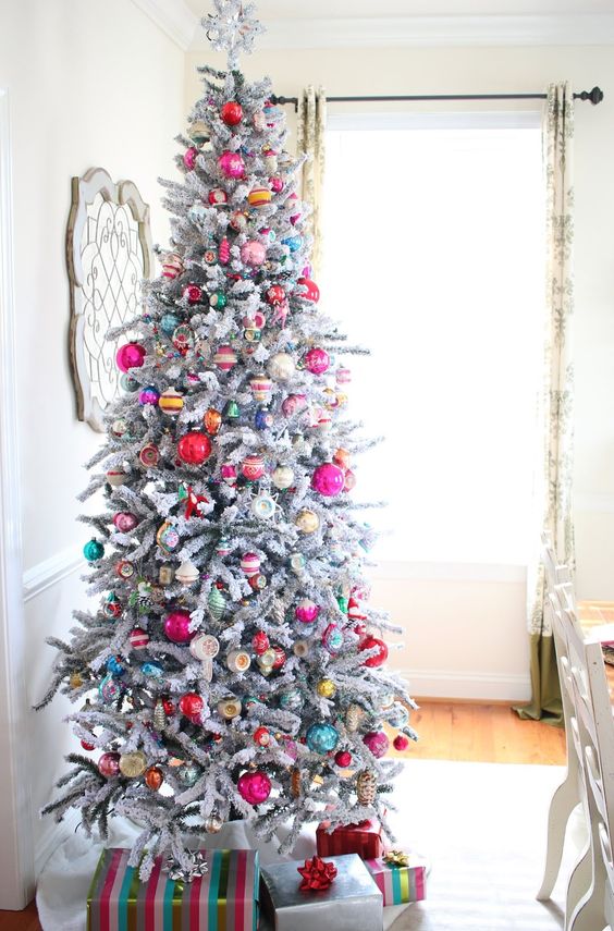 a flocked Christmas tree decorated with colorful vintage ornaments and topped with a star is wow